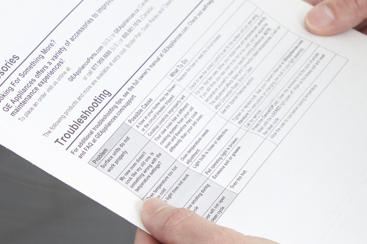 Person reading the troubleshooting section of an oven manual.