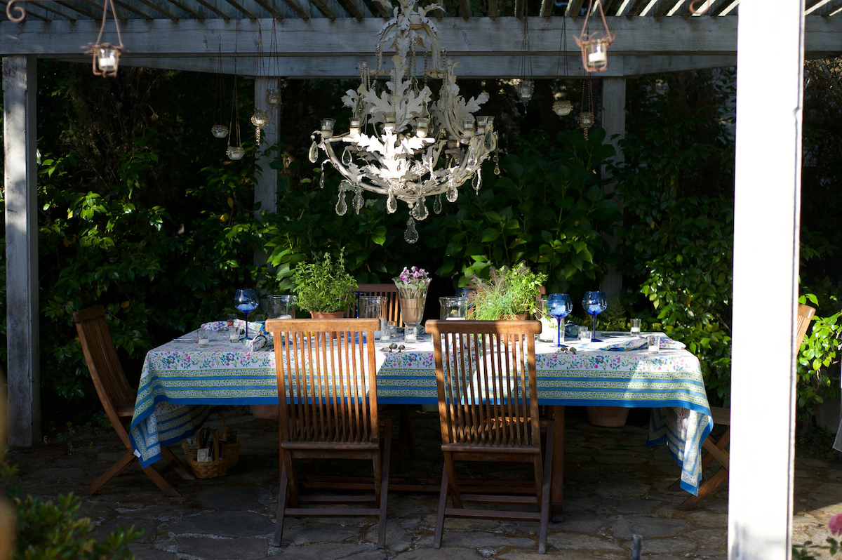 A table set under a gazebo with chandelier for a dinner party.