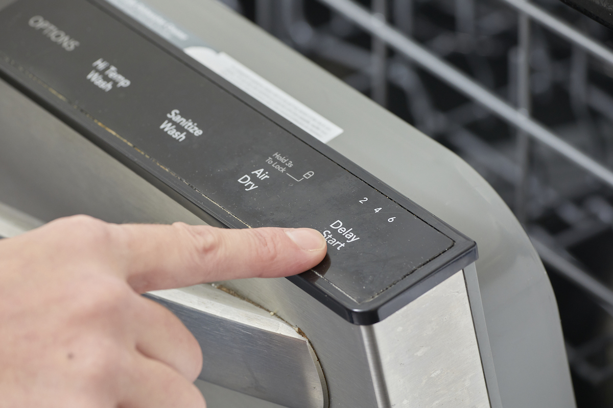 Woman pushes the "delay start" button on her dishwasher.