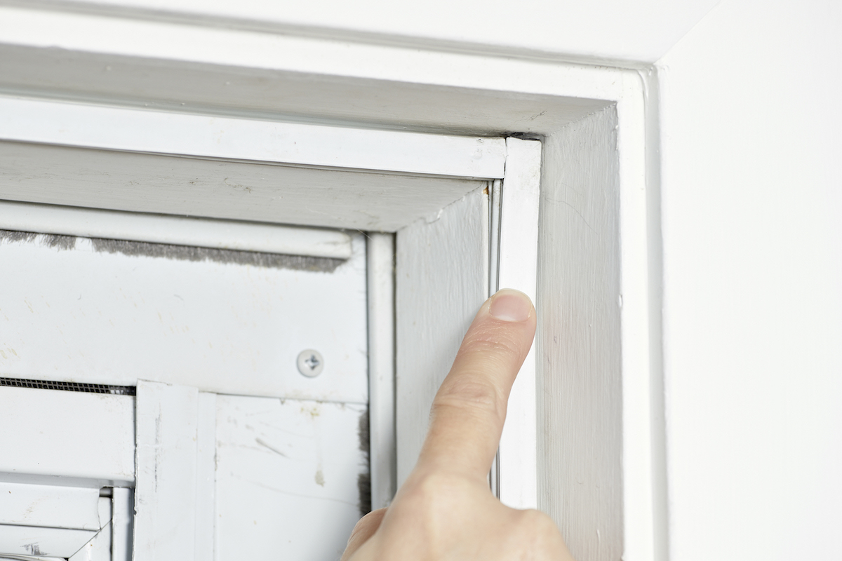 Woman points to weatherstripping around a white door.