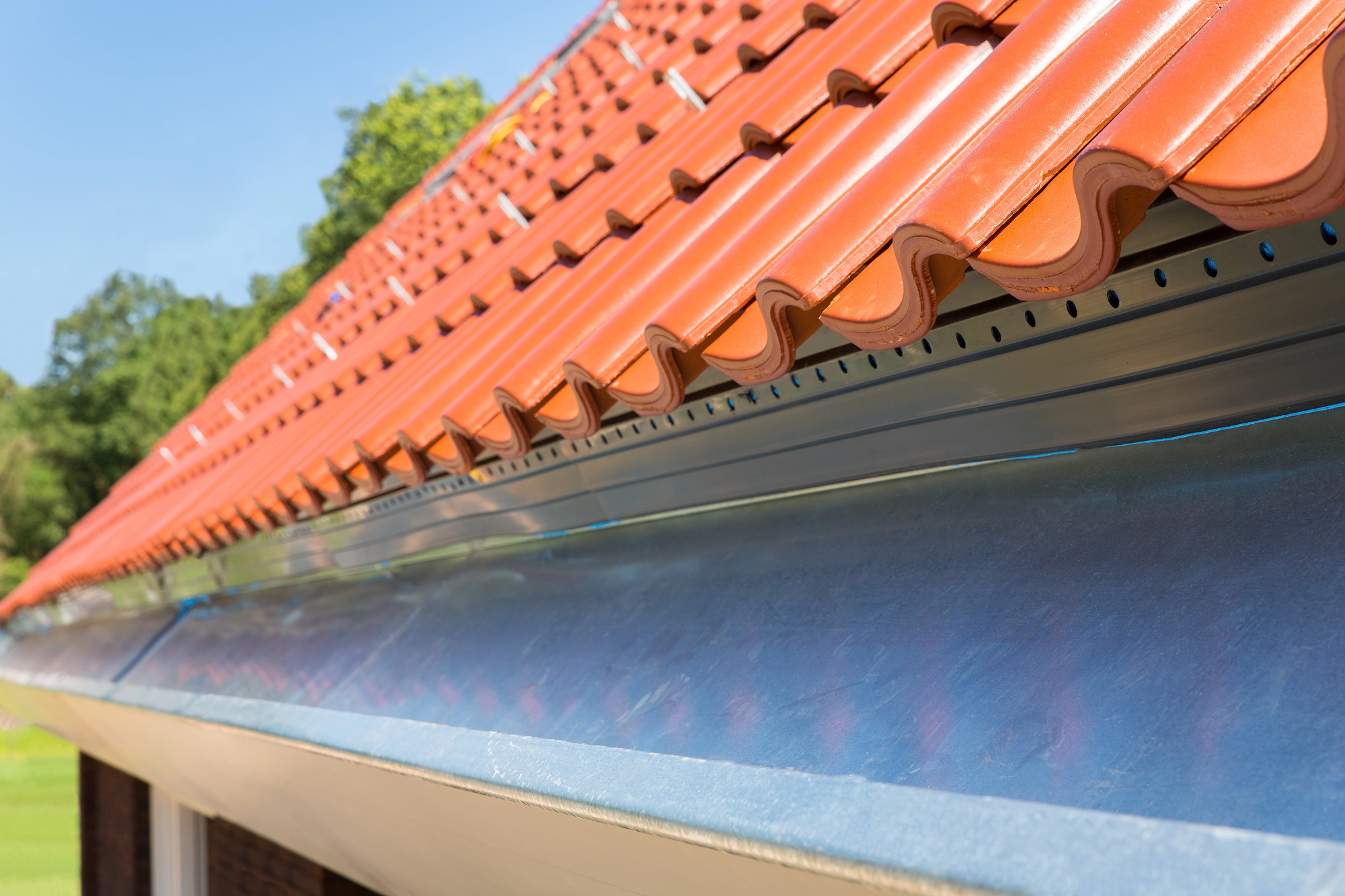 A freshly installed tile roof hangs over equally new aluminum box gutters.