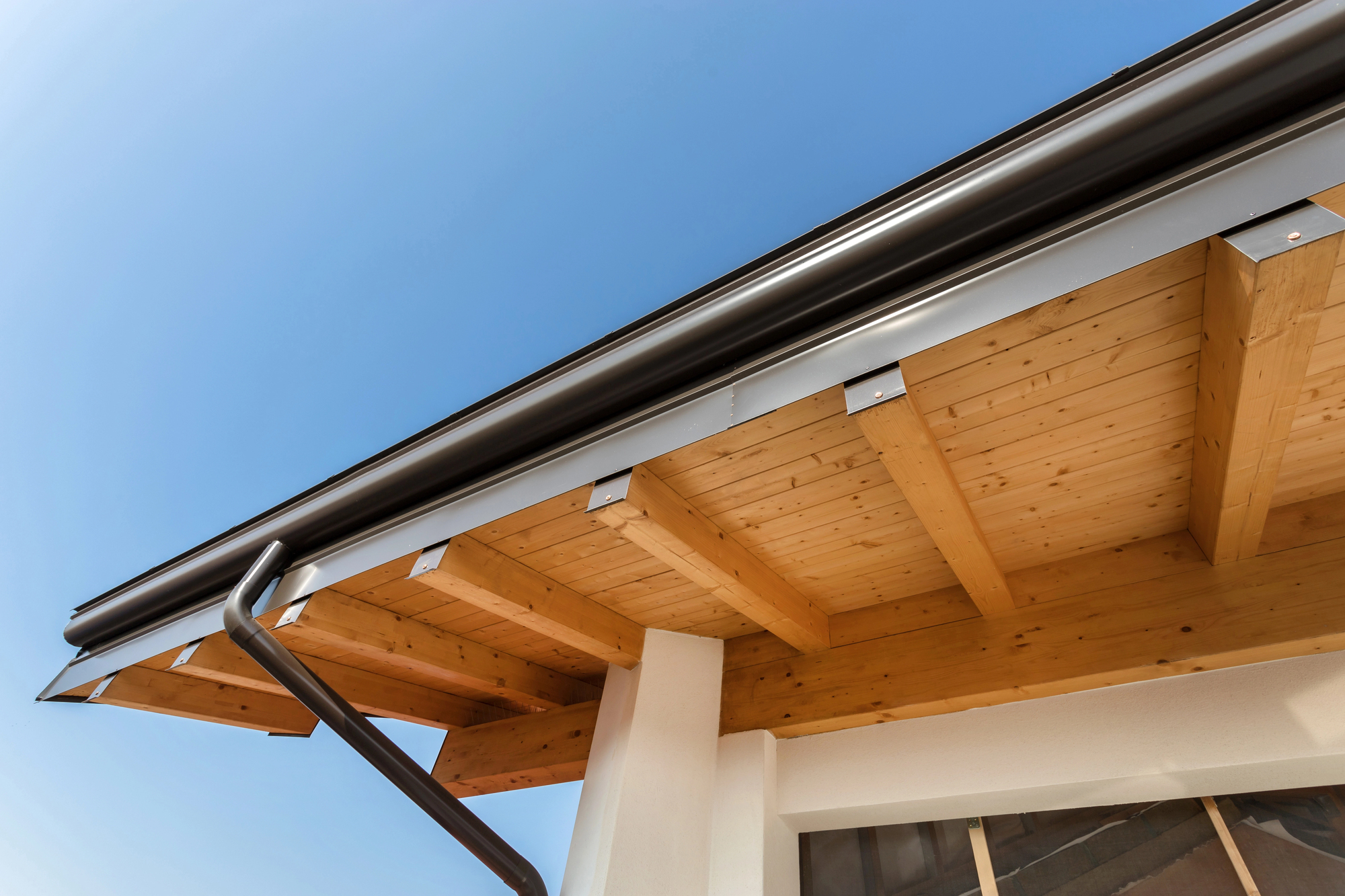 A long, custom-built fascia-style gutter looks brand new on a new construction home.