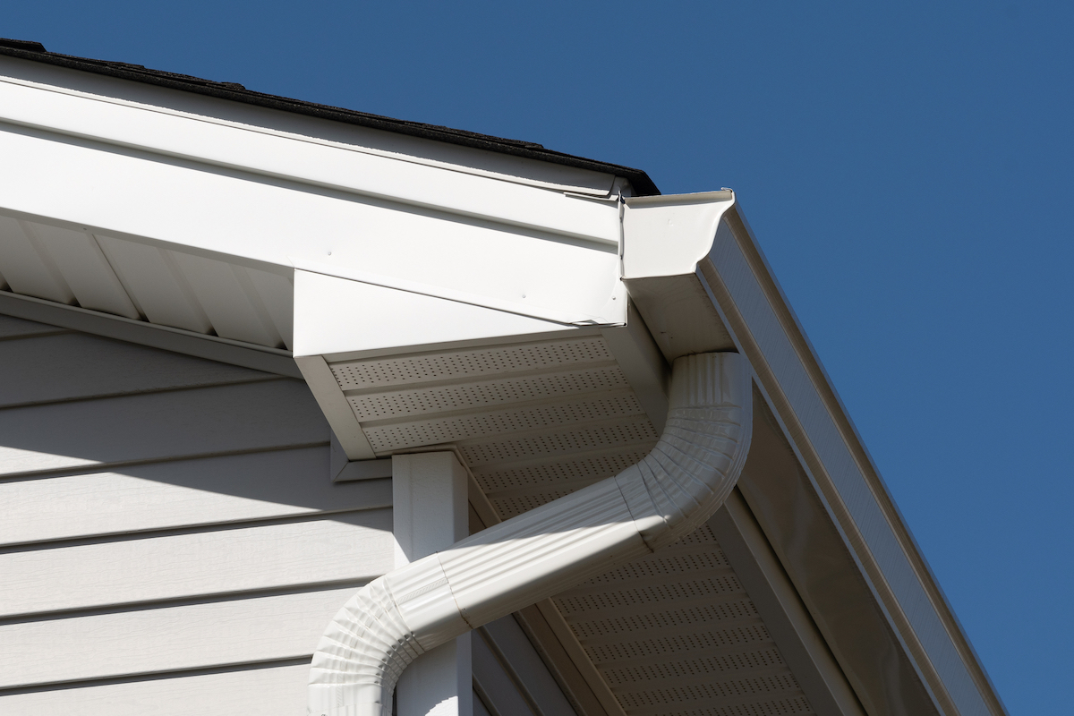 A white K style gutter lines the bottom of the roof of a house.