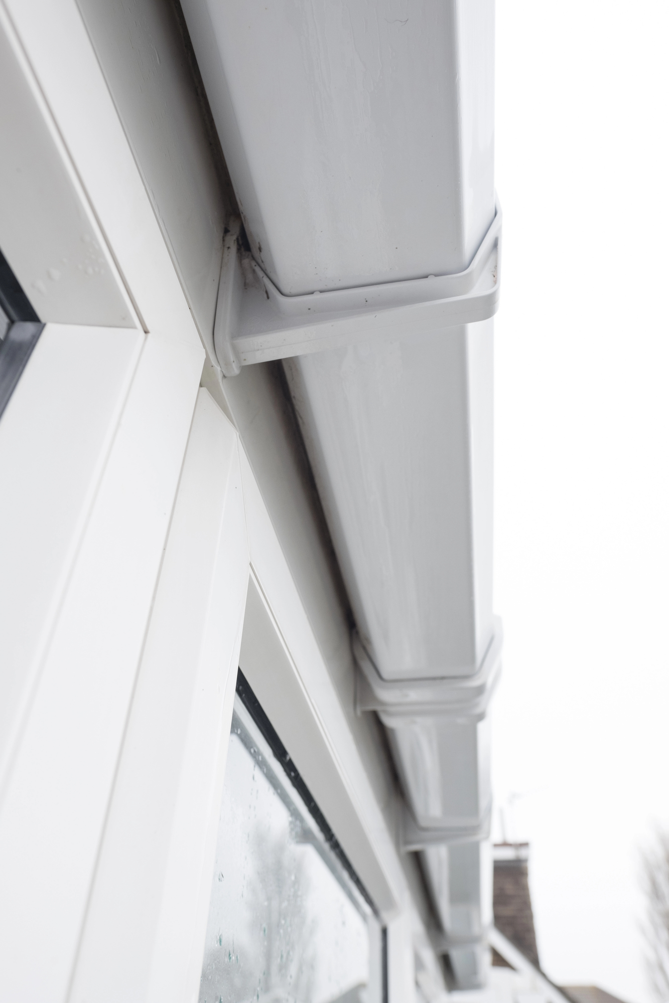 The white vinyl gutters of a house as seen from below.