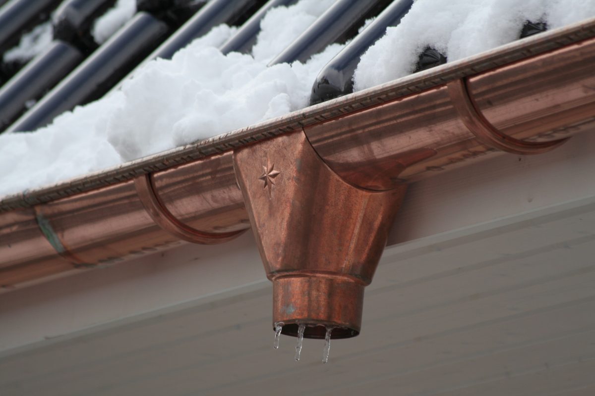 New copper gutters collect small icicles where a downspout will be installed in snowy weather.