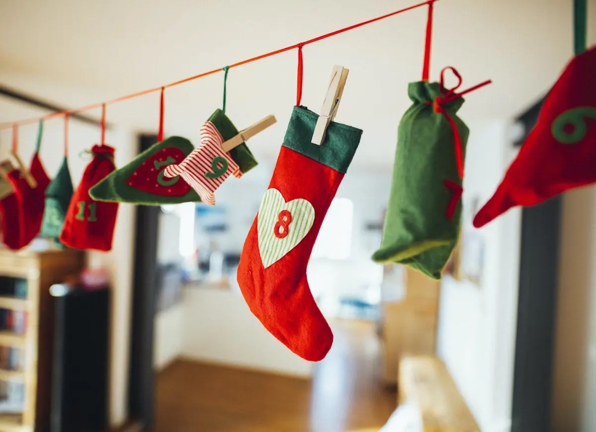 Many numbered felt Christmas stockings in red, white, and green hanging from a string in a living room.