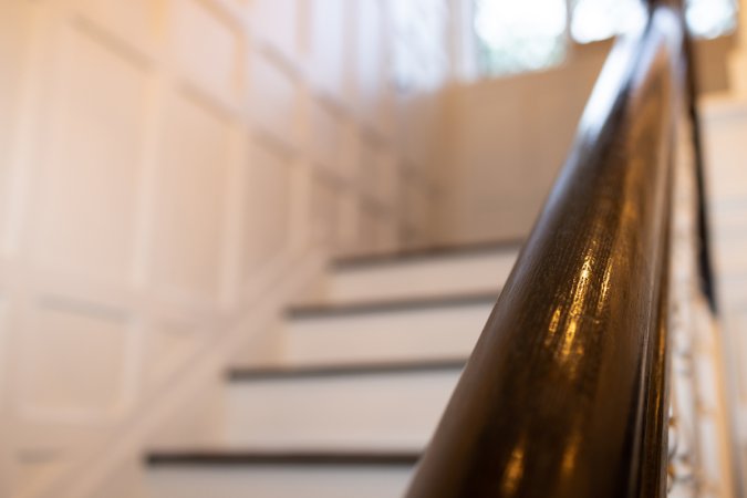 Staircase in an early 20th century Tudor home, with white risers and dark wood treads and handrail.