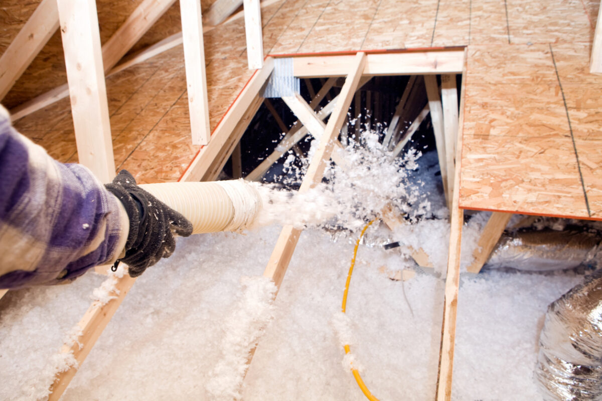 Blown-in insulation being installed between attic trusses.