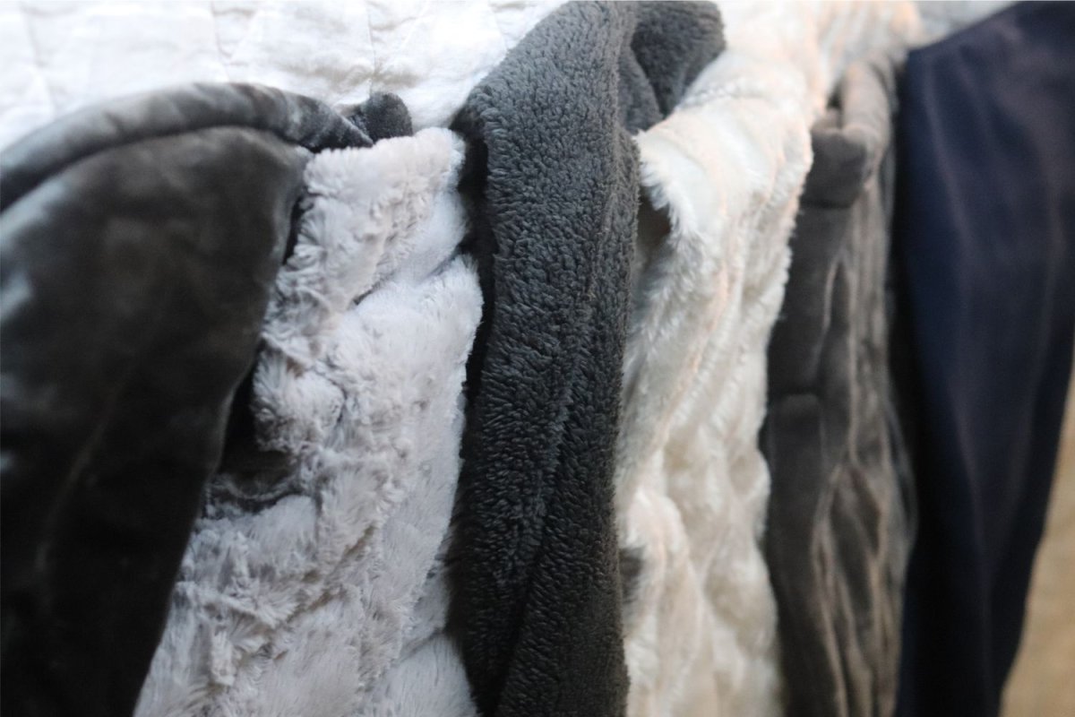 A stack of the best electric blankets placed together, with most options being blue, grey, and white.