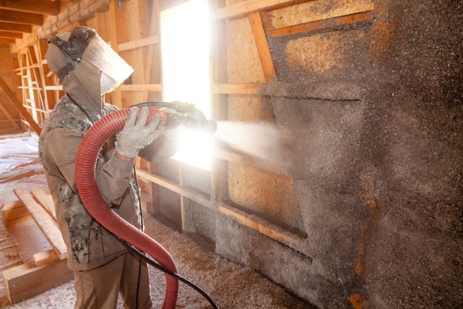 Spraying cellulose insulation on the wall.