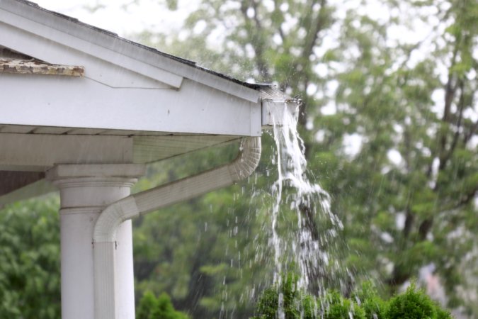 A blocked gutter causing rain to overflow out of the gutters.