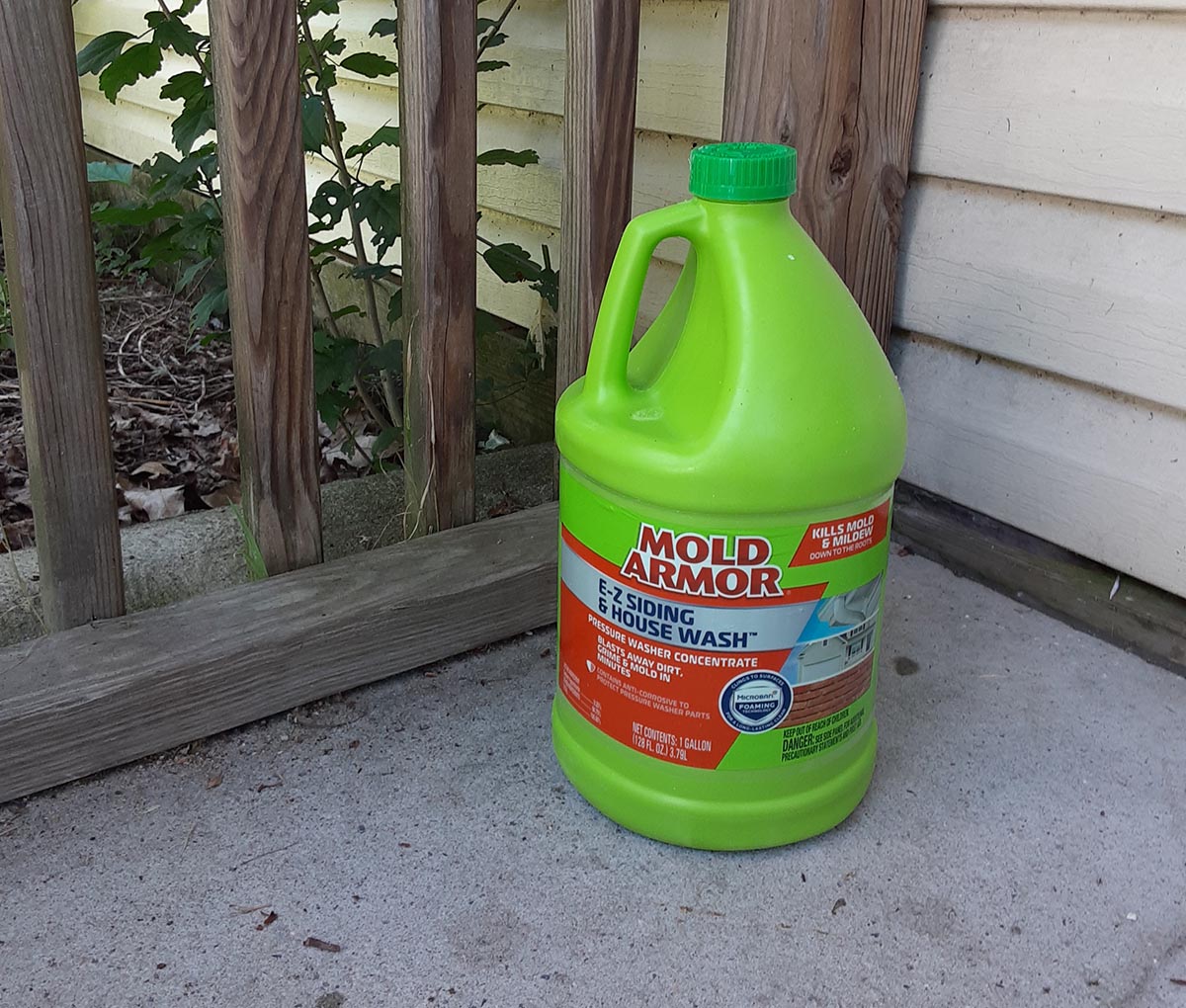 Green bottle of Mold Armor e-z siding and house wash on concrete porch