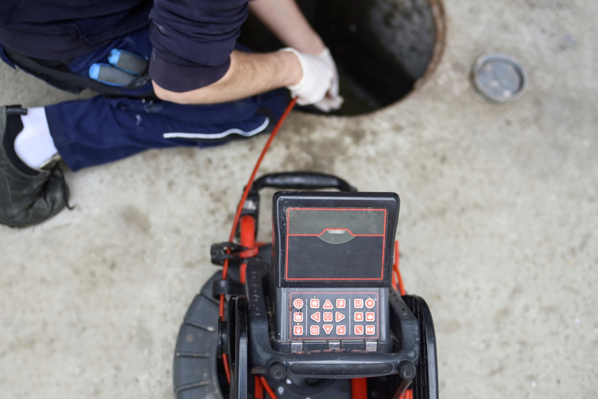 An inspector is looking in a septic system with camera system.