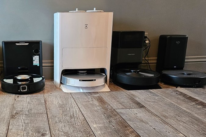 A group of the best robot vacuum options on a wood floor against a wall.