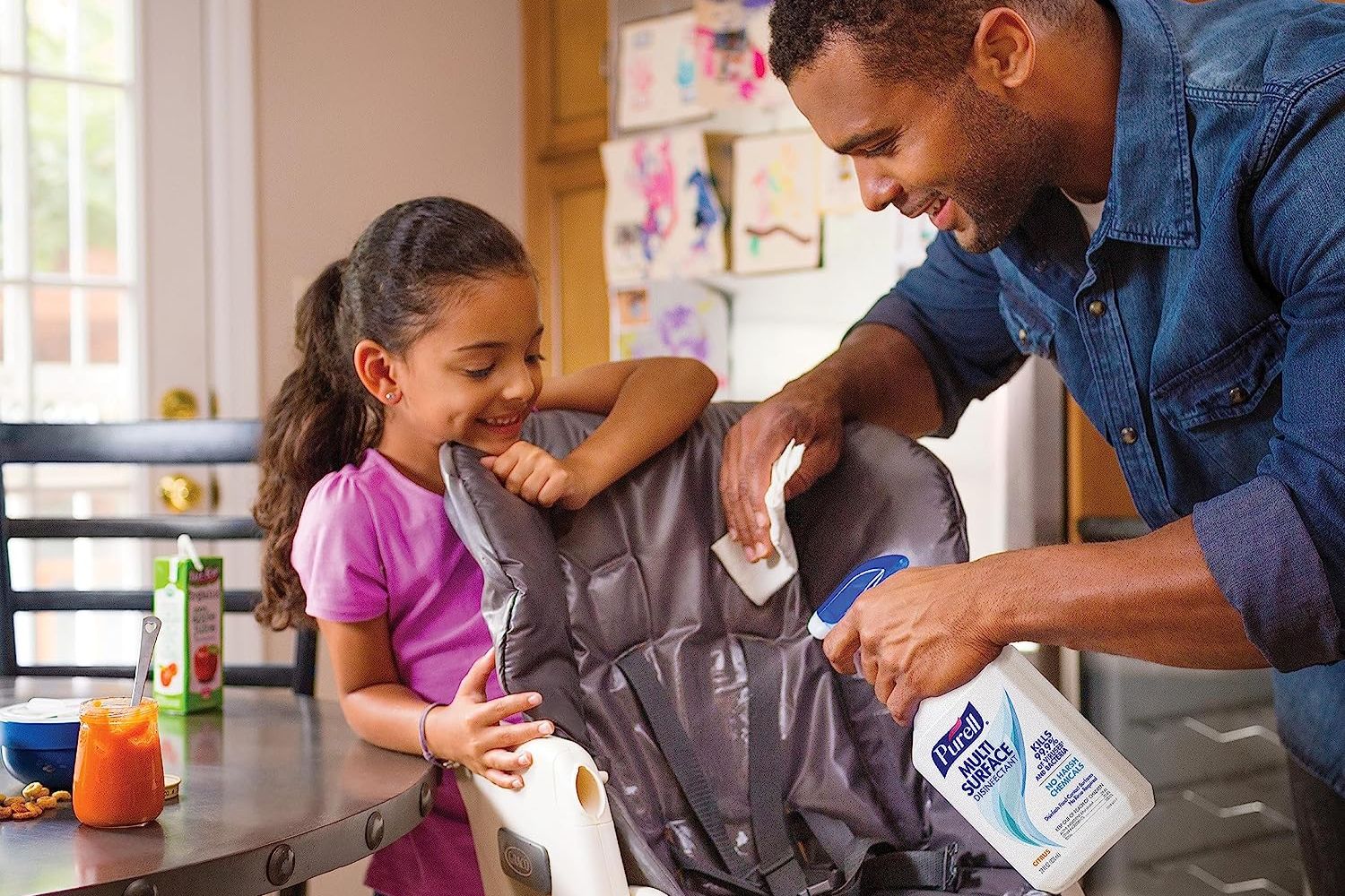 A father and daughter using the best disinfectant spray option to clean a highchair