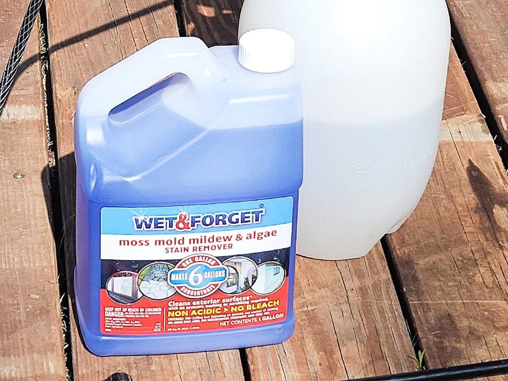 Bottle of Wet & Forget deck cleaner sitting on a wood deck