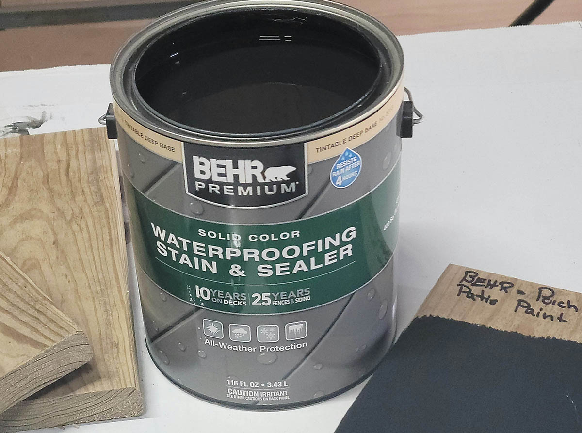 An open can of Behr deck paint on a white table