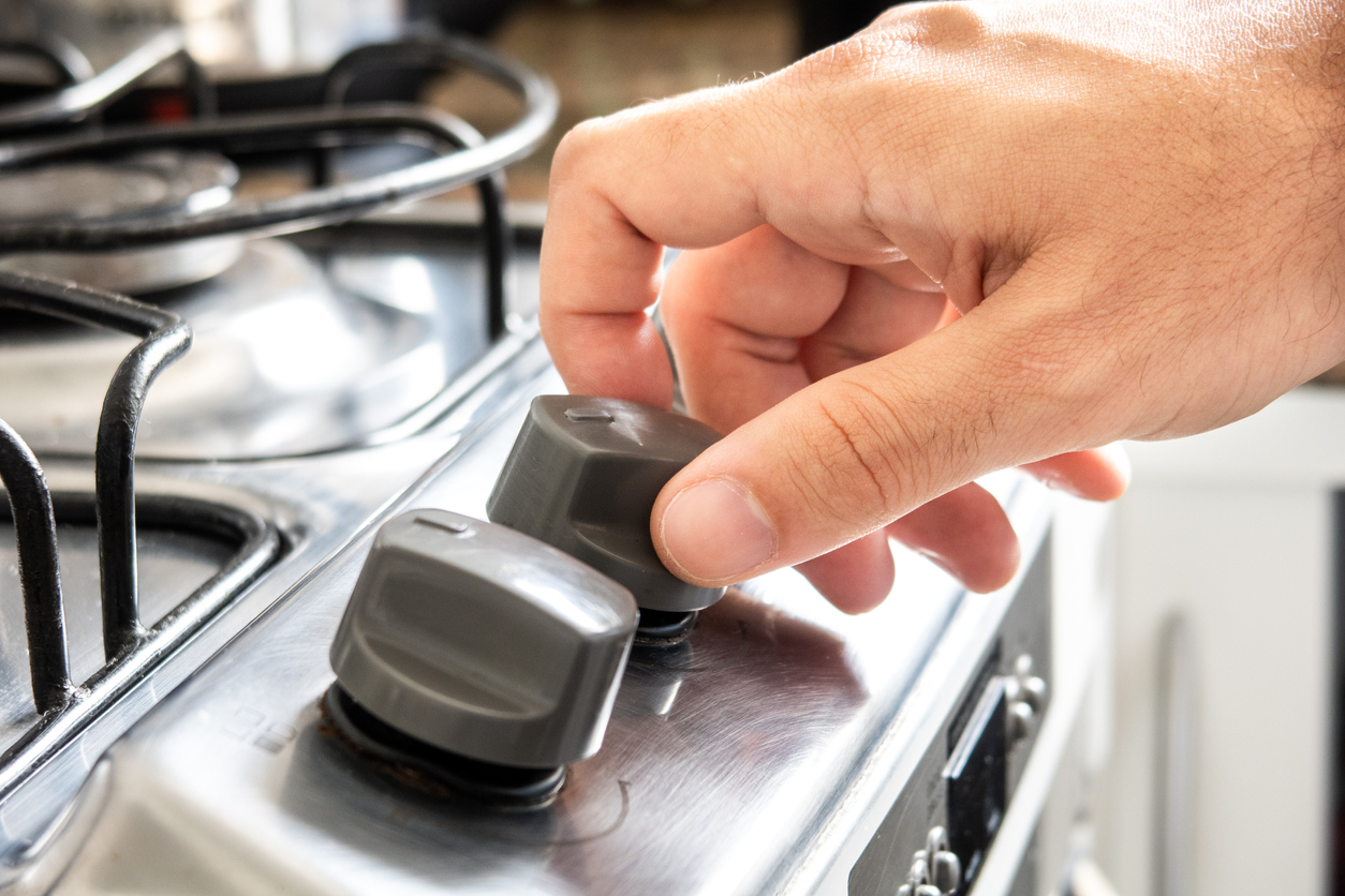 and of a man pressing and turning gas control knobs of a stove.