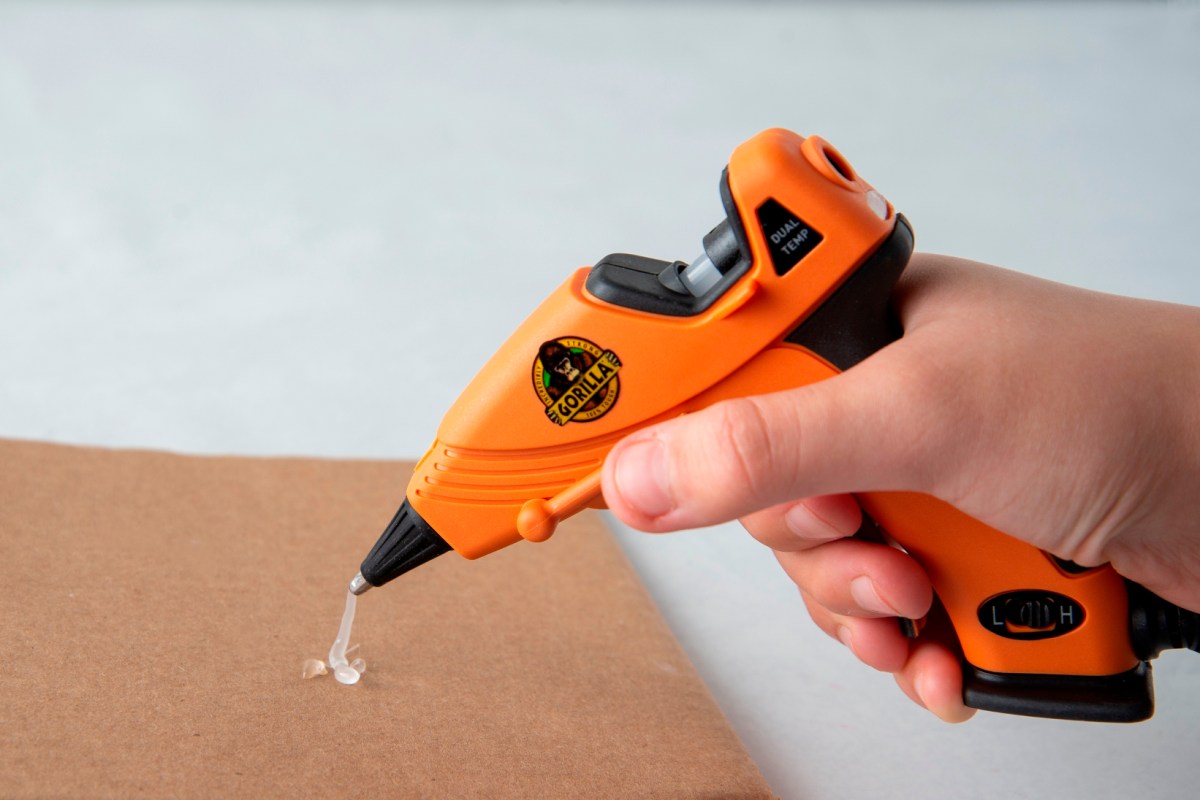The best glue gun option in use with a string of glue getting squeezed out onto cardboard