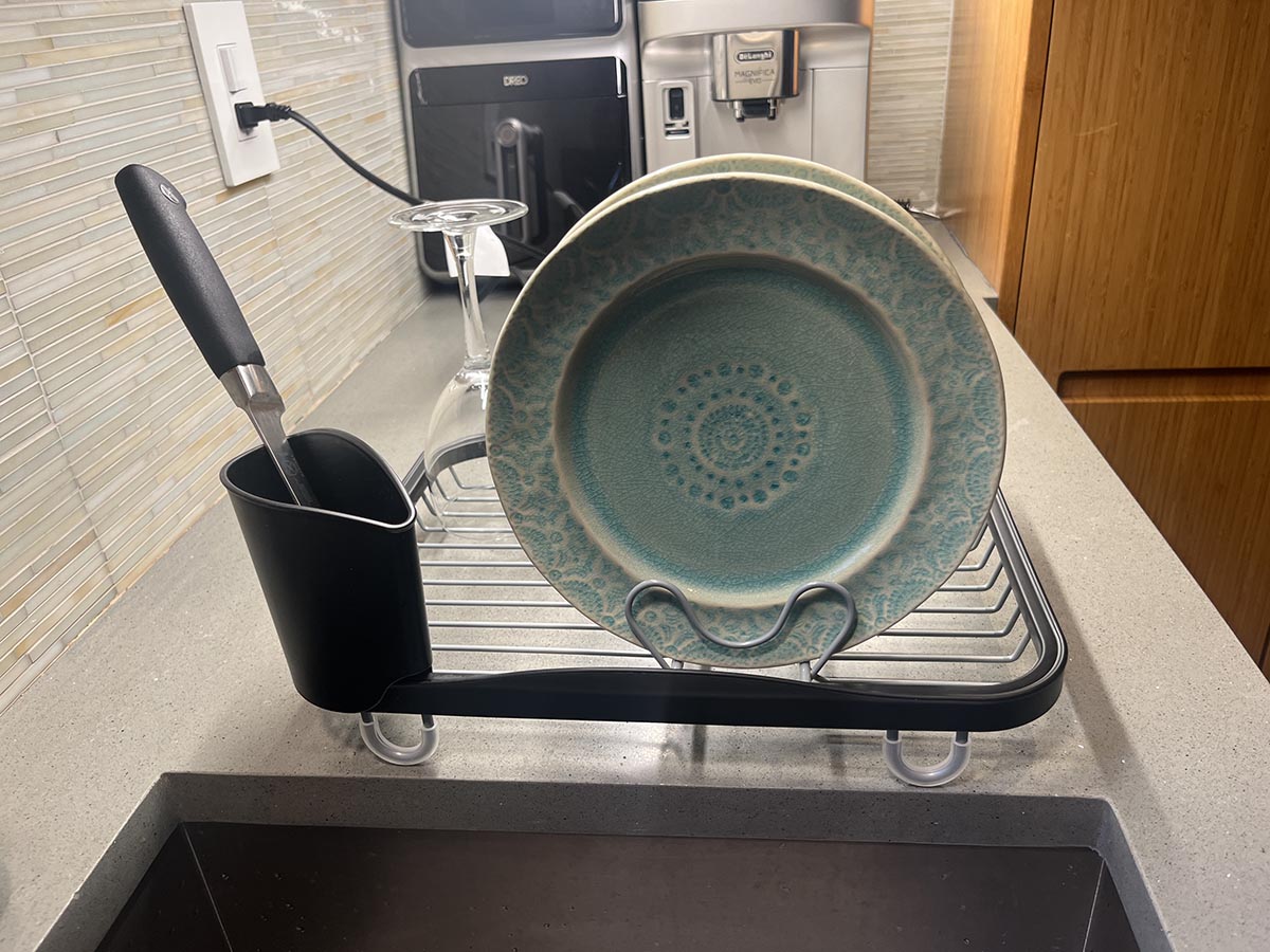 The best dish-drying rack on a kitchen counter with a few dishes in it and some small kitchen appliances in the background.