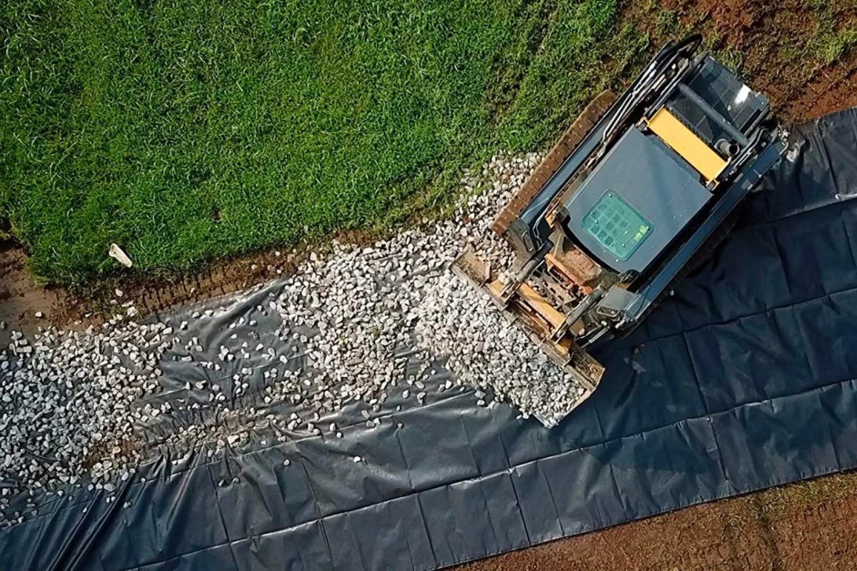 Someone spreading rocks over the best landscape fabric option