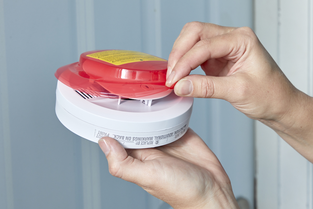 Woman pulls tab to activate battery on smoke detector.