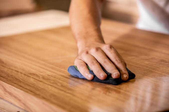 Wiping down a wooden surface to remove wood stain.