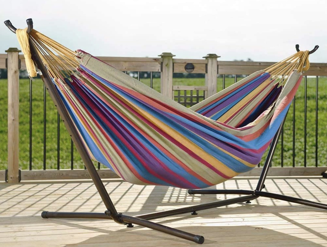 A colorful freestanding hammock outside on a deck 