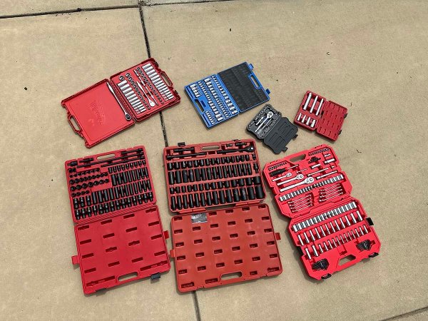 The Best Socket Sets Options laid out in their cases on a cement sidewalk