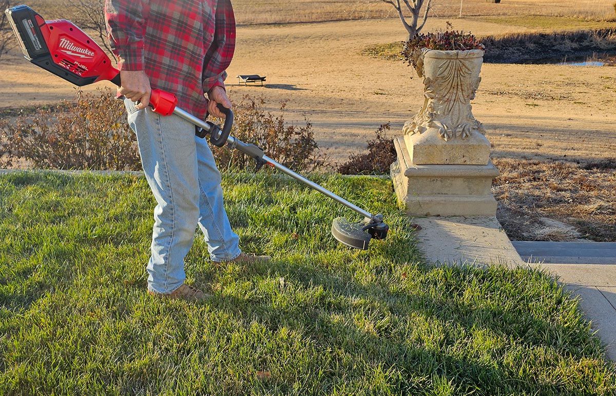 A person using the Echo DSRM-2100 eForce 56V String Trimmer to tidy the edge of a lanw.