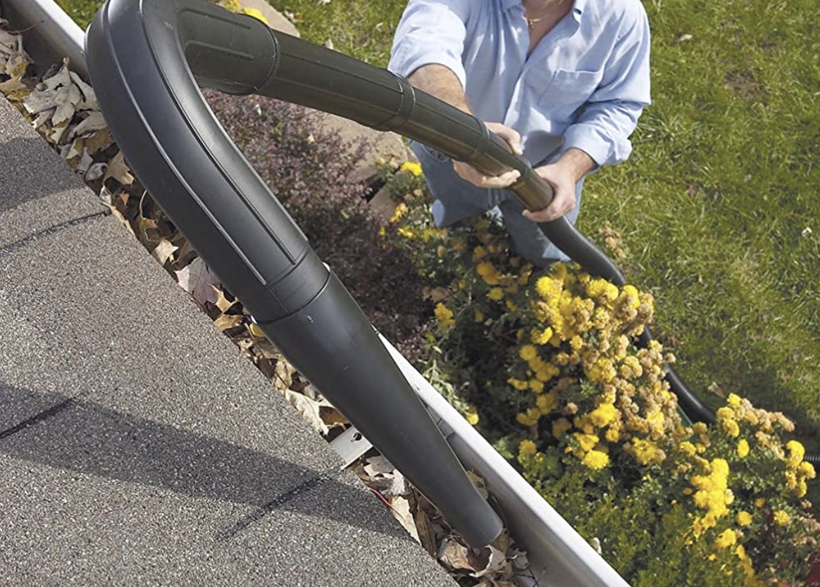 Man cleaning a gutter with a long black vacuum
