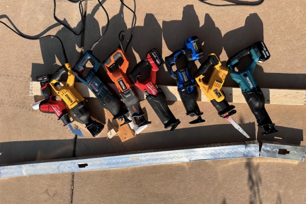 Eight of the Best Reciprocating Saws resting on a 2 by 4 on a concrete driveway