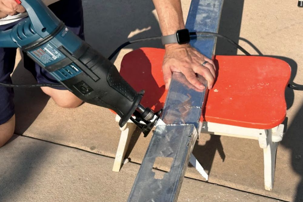 Person using a Bosch reciprocating saw to cut through metal ductwork