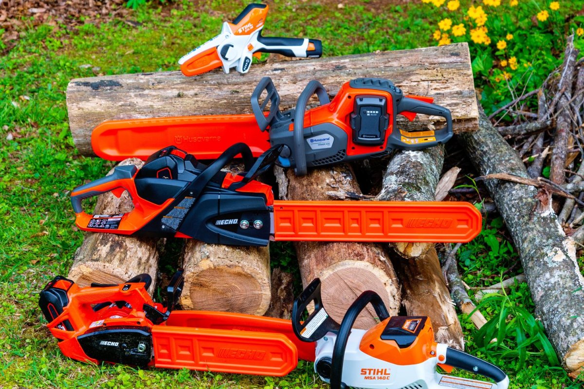 A group of the best battery chainsaws pictured together on a stack of logs