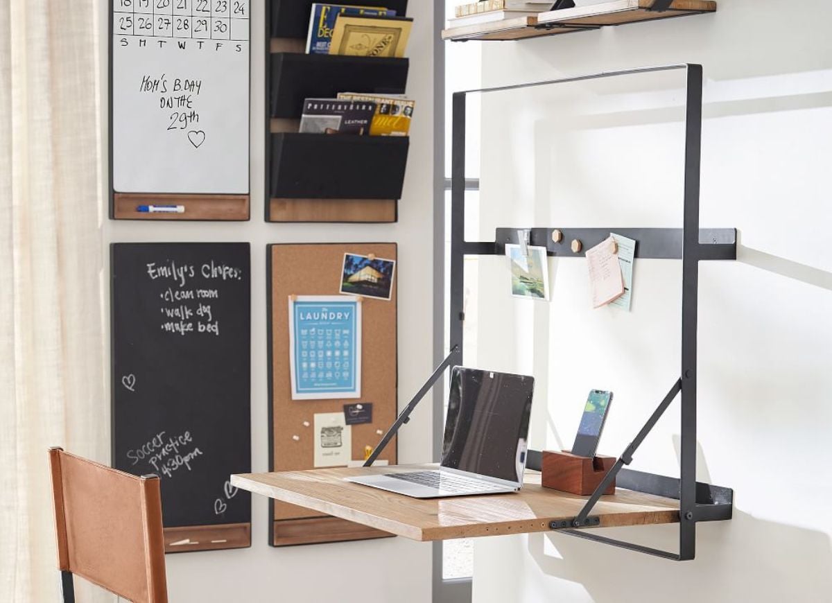 A home work station with a wall-mounted desk unit, bulletin boards, and sticky notes.