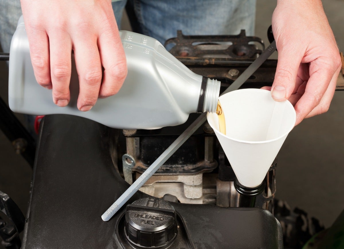 Pouring gas into a snowblower using a cone funnel.