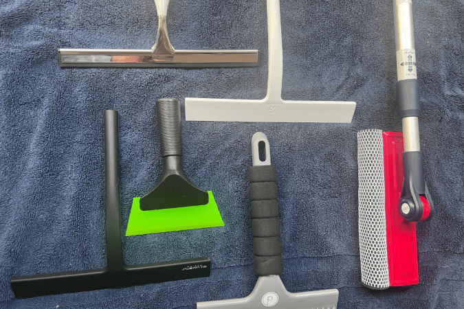 A group of the best shower squeegees grouped together on a towel before testing.