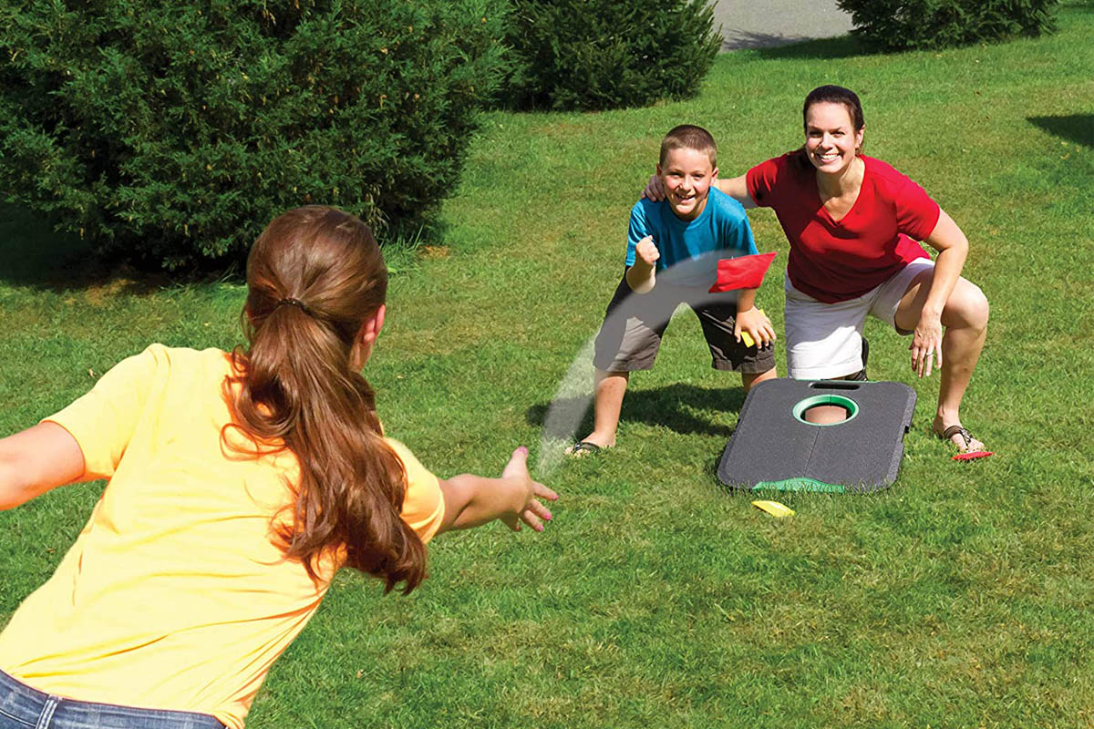 The Best Cornhole Board Option in use by two adults and a child in a yard