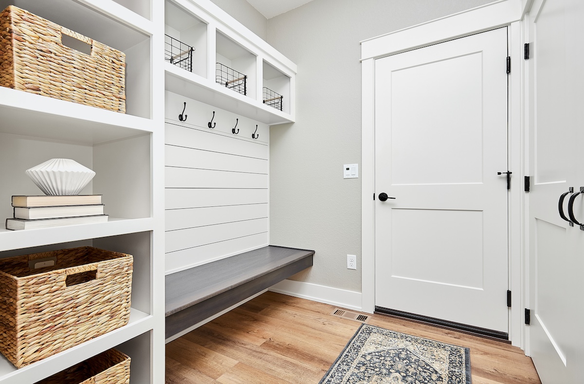 A clean mudroom with organized cubbies is white and gray.