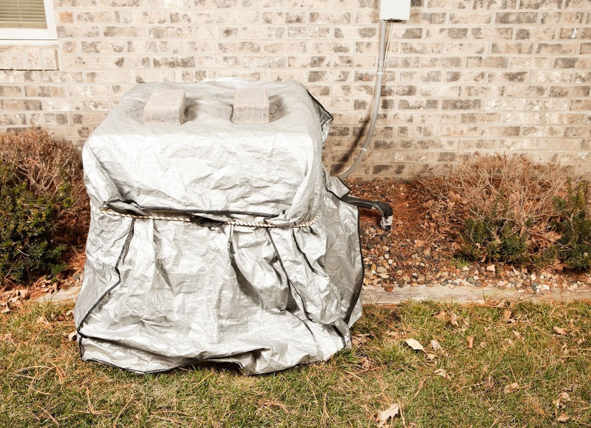 An AC unit covered with a tarp to keep it clean.