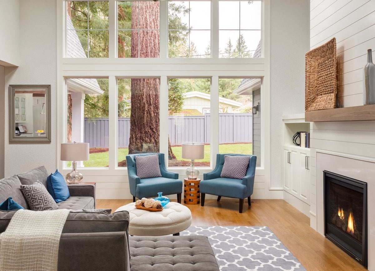 A living room with a beige, blue, and tan color scheme with bright storm windows.