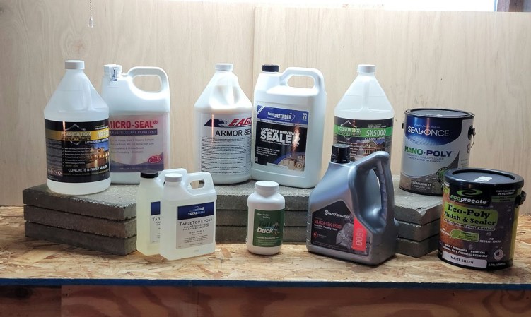 Several bottles of different concrete sealer brands lined up on a table