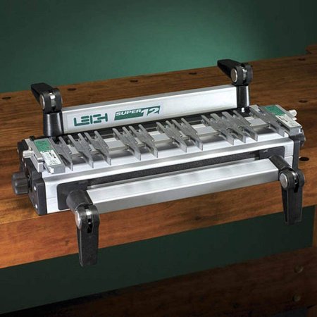  The Leigh Super12 12-Inch Dovetail Jig on a dark-stained wood bench with a green background.