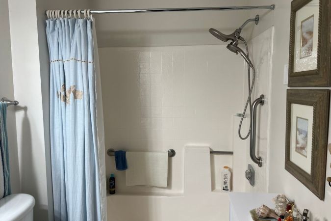 Chrome shower curtain rod holding up curtain in white bathroom