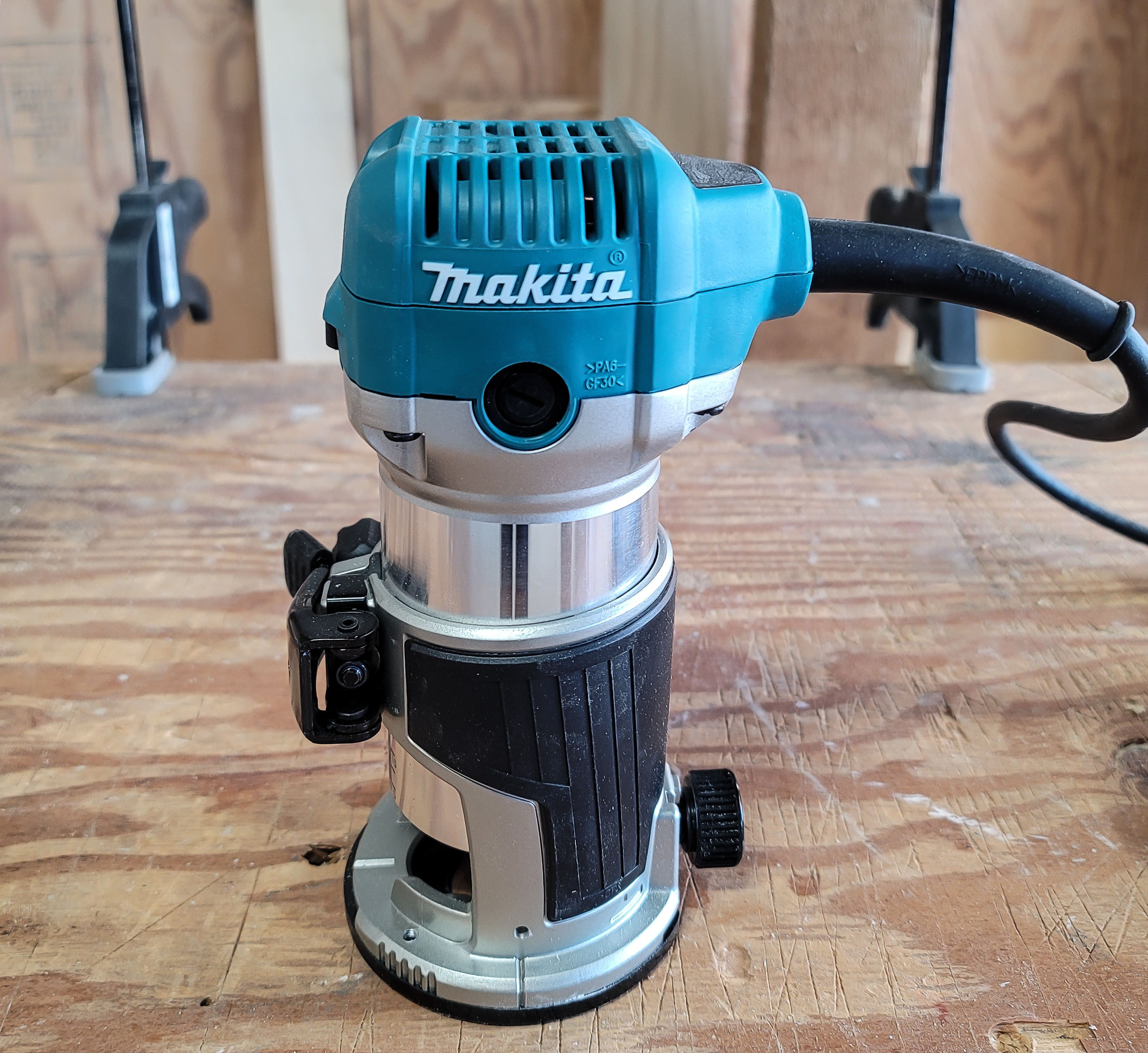 Makita corded palm router on top of a piece of clamped wood