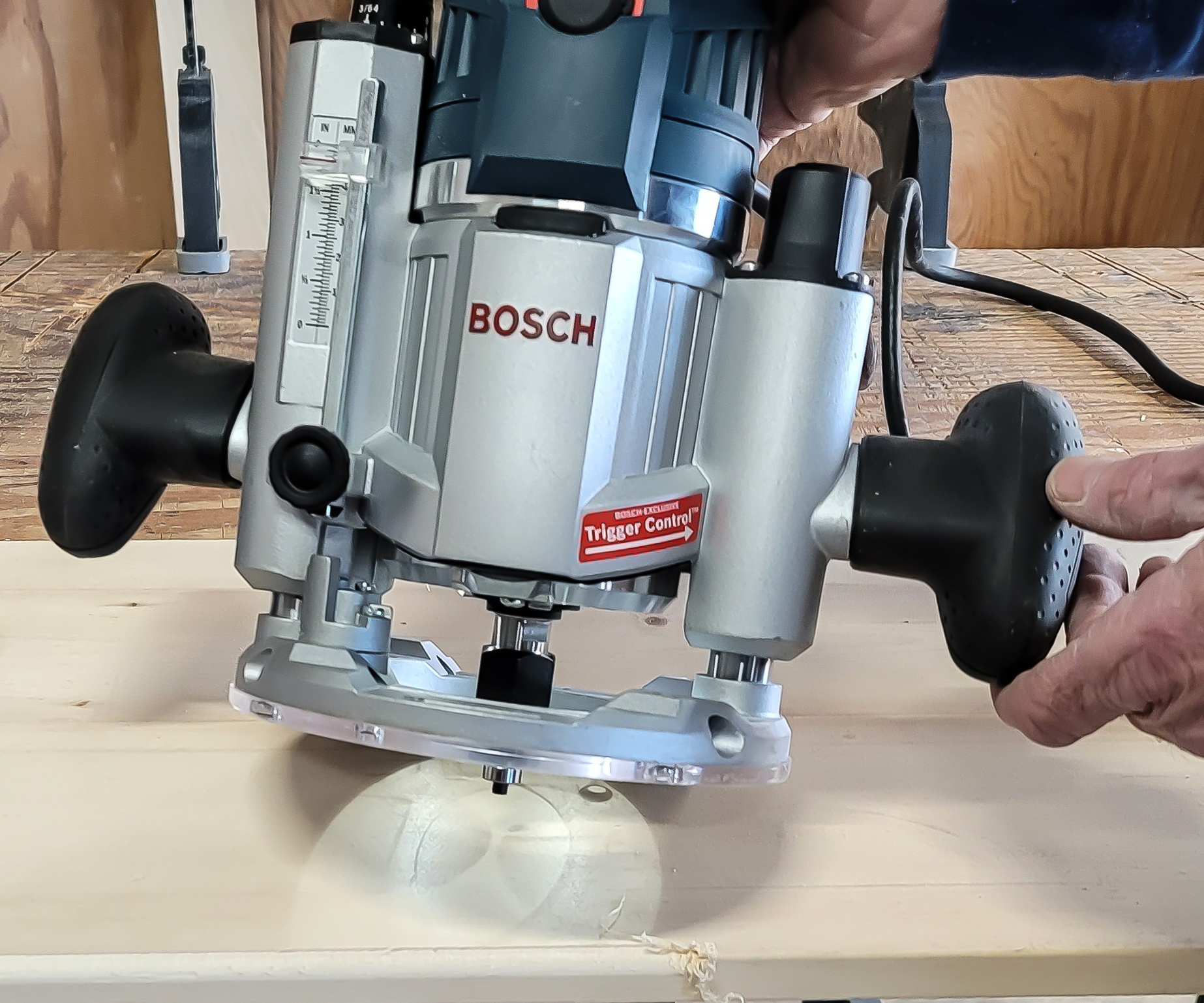 Person shining a guide light on a Bosch plunge base router in the middle of a workpiece