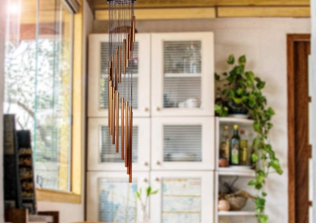 The best wind chime option hanging in the foreground with a wooden hutch, dishes, and plants in the background