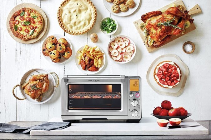 An oven air fryer surrounded by various food dishes