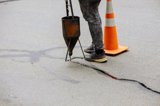 A person using the best asphalt driveway crack filler option to fill a crack