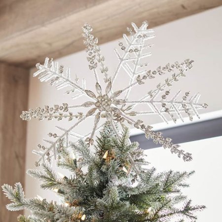  The Pottery Barn Jeweled Snowflake Christmas Tree Topper on a tree with a white wall, wooden ceiling beams, and window in the background.